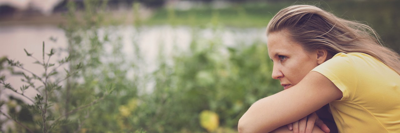 Tips for Living With Anxiety and Depression Woman crouched by a lake
