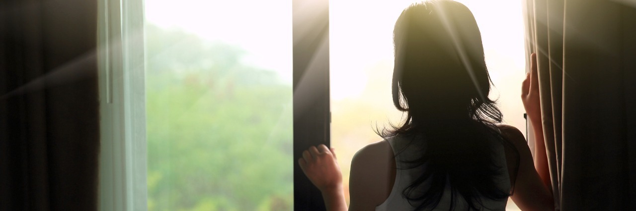woman looking out window at sunlight