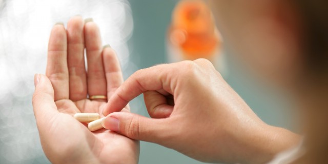 Close up view of young woman holding pills