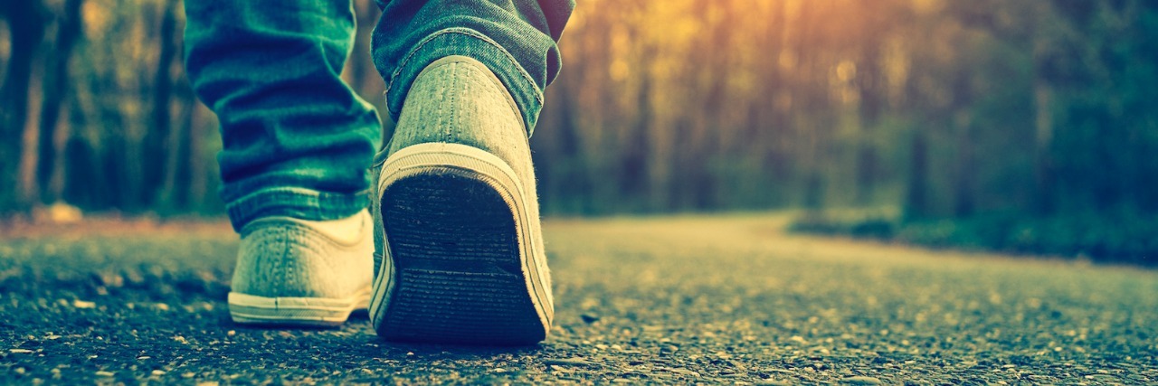 My Experience With Secondary Infertility and a PCOS Diagnosis Close-up of person wearing jeans and shoes, walking on tree-lined road