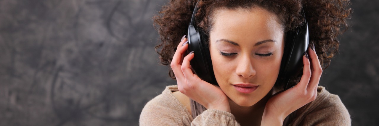 Playlist of Songs for Coping With Chronic Illness Young woman listening to music with headphones