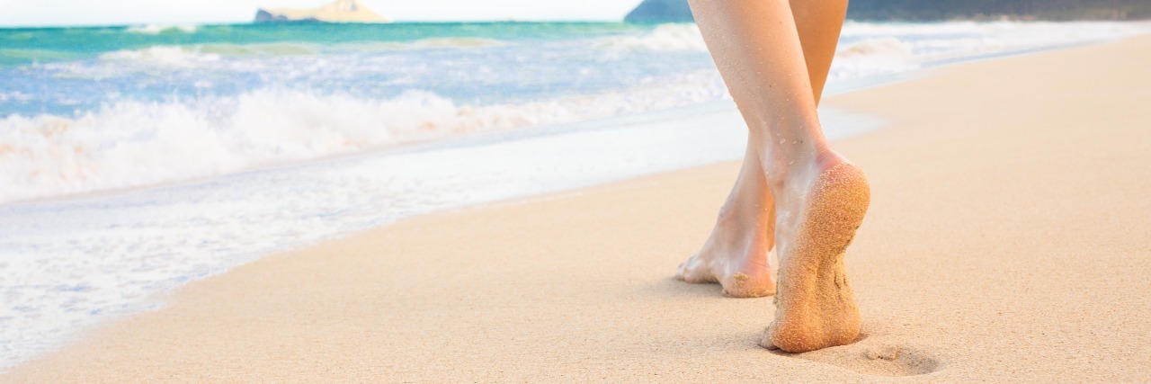 woman walks on beach toward ocean