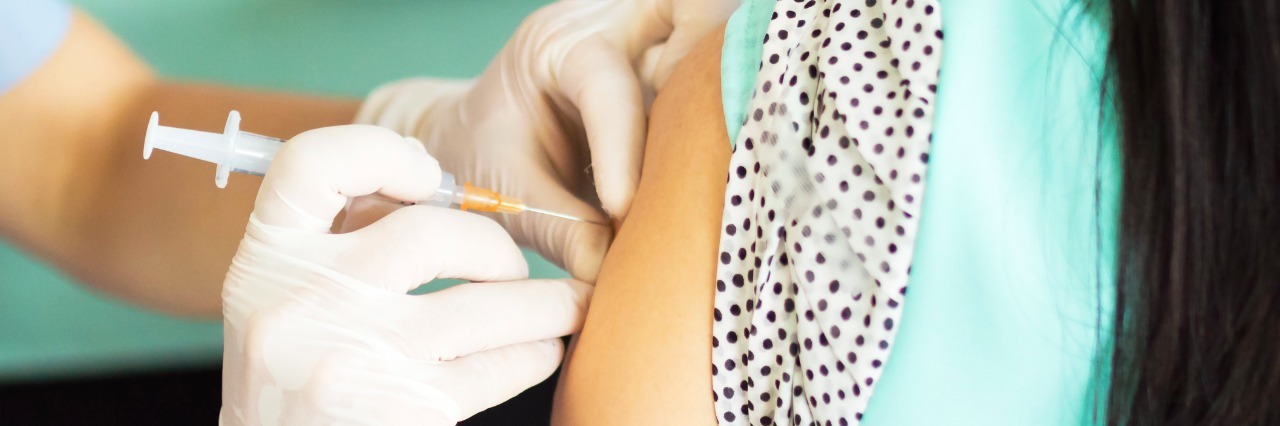 doctor giving woman an injection in her upper arm