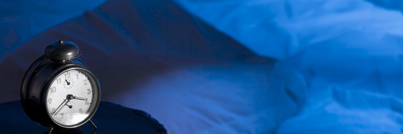 Helping My Daughter on the Autism Spectrum Sleep More at Night Empty bed with an alarm clock on the table beside it at night