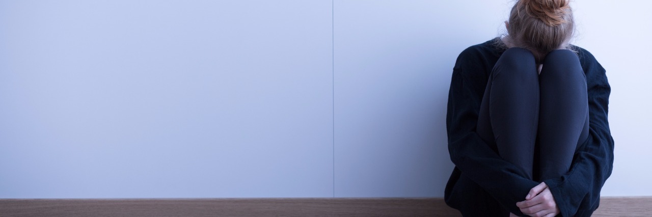 Why Not to Tell Someone to 'Push Through the Pain' girl sitting on floor with knees up and face buried in knees