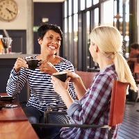 two female friends chatting and drinking coffee