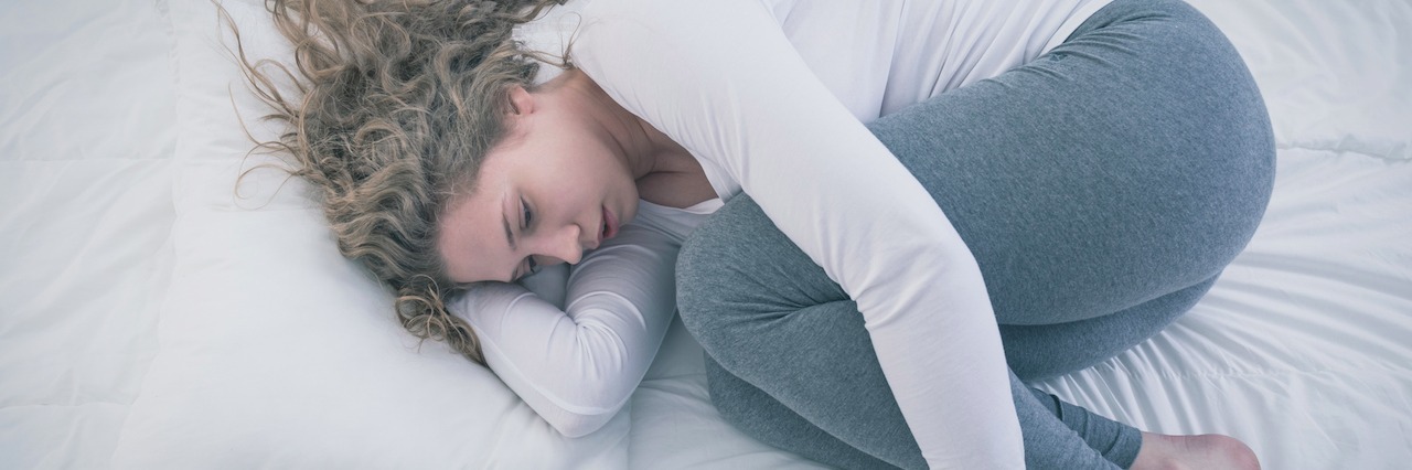 Why You Should Talk About Being Suicidal Even When You're Afraid woman curled up in bed