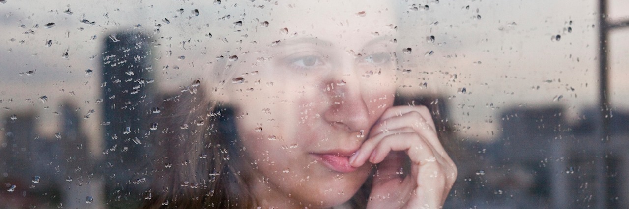 What to Know When Friends and Family Don't Understand Your Anxiety A woman looking at her window on a rainy day