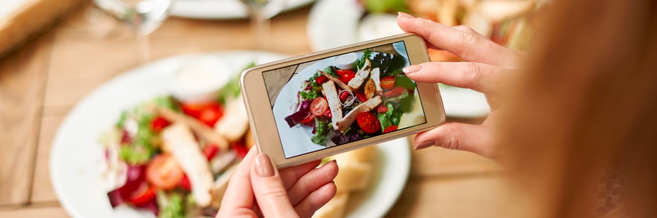 #EDRecovery: How Instagram Helped and Hurt My Eating Disorder Recovery a woman taking a picture of her salad with her phone camera