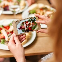 a woman taking a picture of her salad with her phone camera