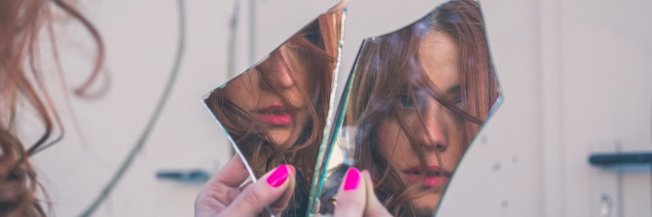 girl looking in her reflection in a broken mirror
