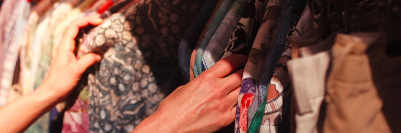 Deciding What to Wear for Going Back to Work After New Diagnosis woman's hands looking at shirts hanging on rack