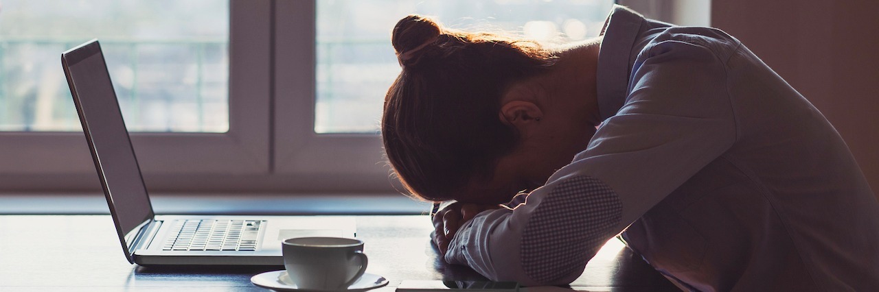 Why 'Choose Happiness' Memes Hurt People With Depression woman with her head down on the table sitting in front of her laptop