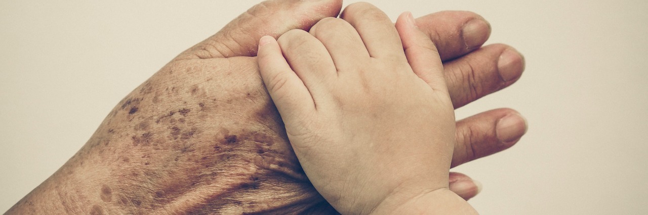 How to Help a Grandmother Who Lost Her Grandchild to Suicide hand of a senior holding the hand of a young child