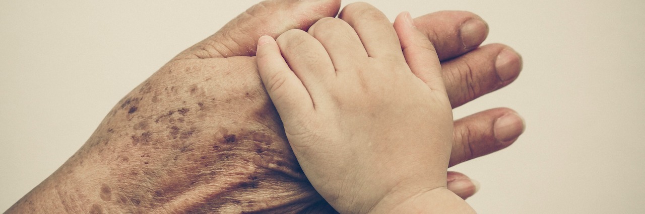 hand of a senior holding the hand of a young child