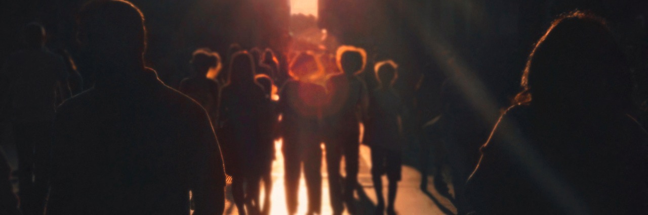 group of people walking towards light
