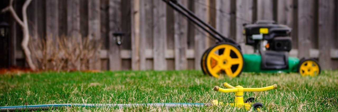 lawnmower and a sprinkler in a backyard