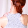 back view of woman rubbing top of shoulder
