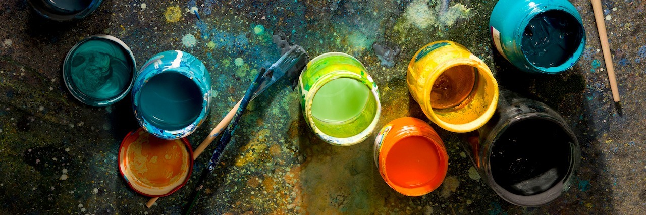 table splattered with paint cans and paint brushes