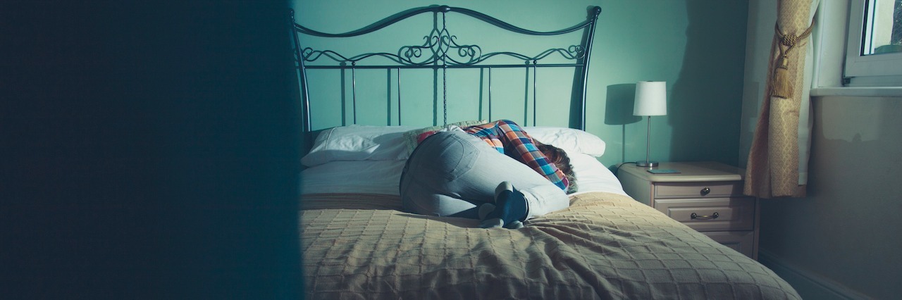 What It's Like to Have a Panic Attack First Thing in the Morning A woman laying in bed fully dressed