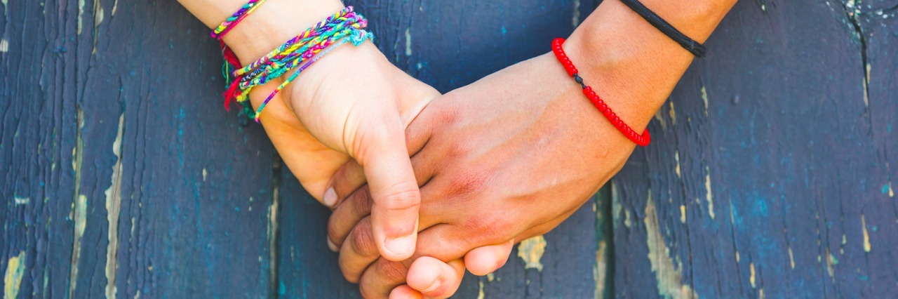 Hashimoto's Disease: Lessons From Living With an Autoimmune Disease Two women holding hands on a blue wooden background