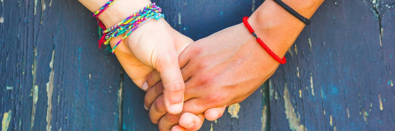 Two women holding hands on a blue wooden background