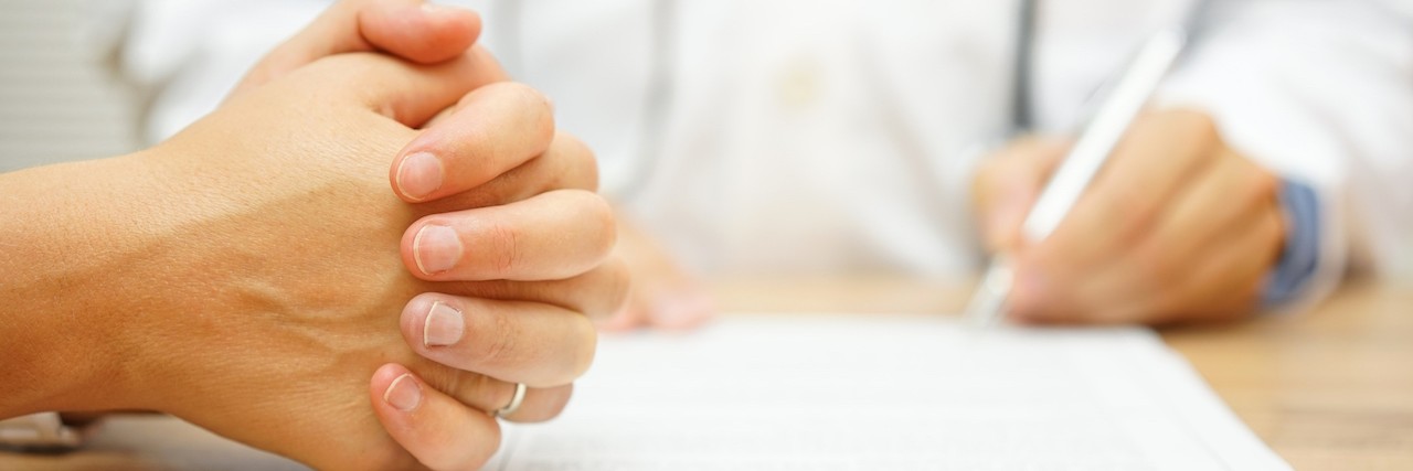 Finally Trying Medication as a Mom With Anxiety a woman grasping her hairs together while talking to a doctor
