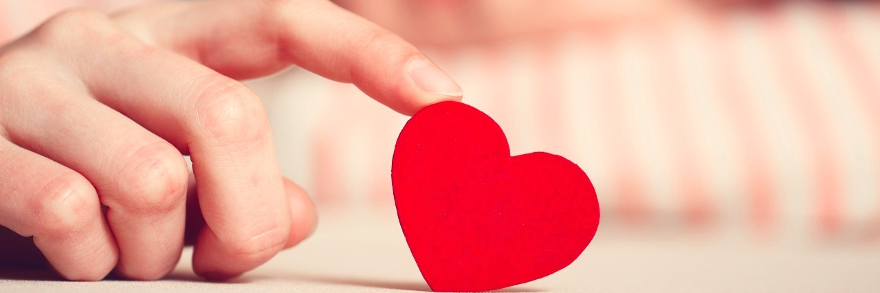 The Gift of Second: The Realistic Path of Grief After Suicide Loss sad girl is holding heart symbol by her finger