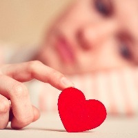sad girl is holding heart symbol by her finger