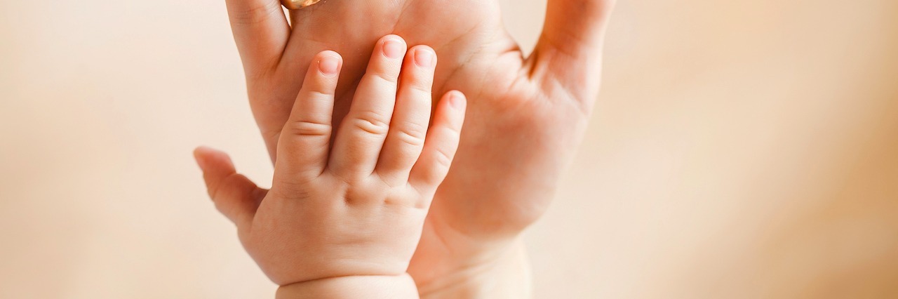 Small hand of a newborn baby lying on her mother's big palm,