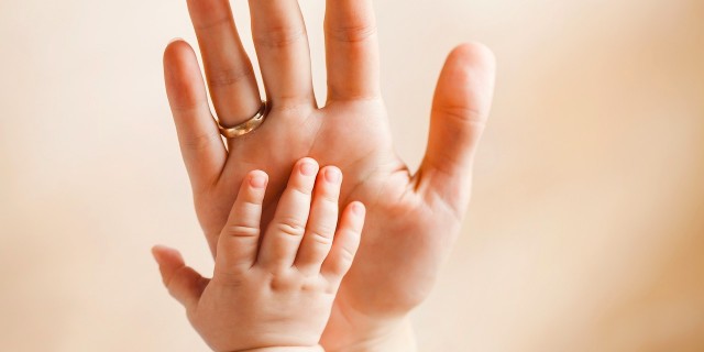 Small hand of a newborn baby lying on her mother's big palm,