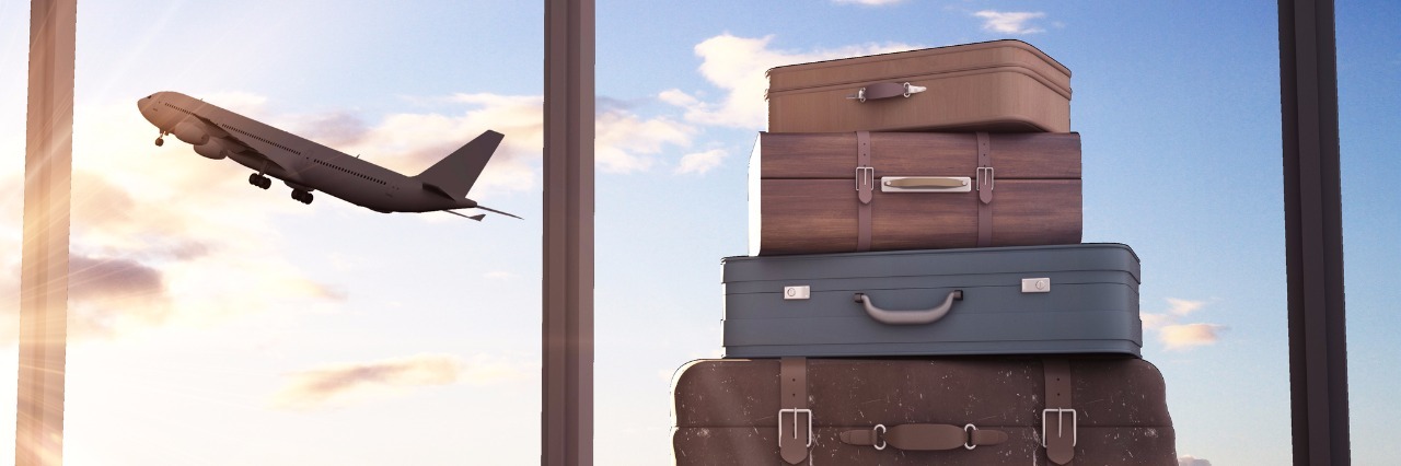 Traveling With Autism and Mast Cell Activation Disorder a stack of suitcases in front of a window where you can see a plane taking off