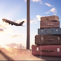 a stack of suitcases in front of a window where you can see a plane taking off