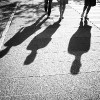 three shadows of people walking down street