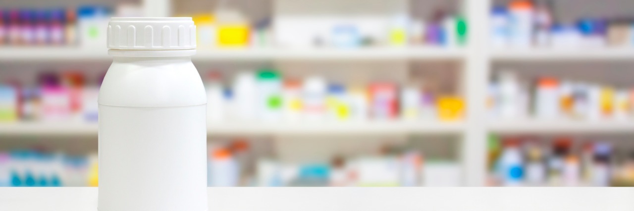 Blank white medicine bottle on counter with pharmacy drugstore