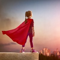 girl standing on building wearing a red superhero cape