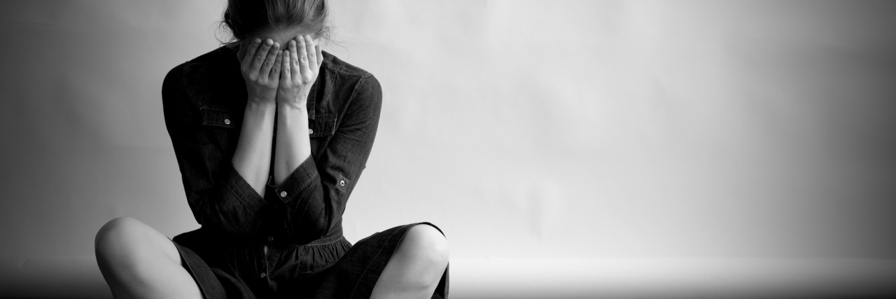 Alone, Undiagnosed, Afraid, and Needing Advice Woman is sitting on an old floor with cracks.