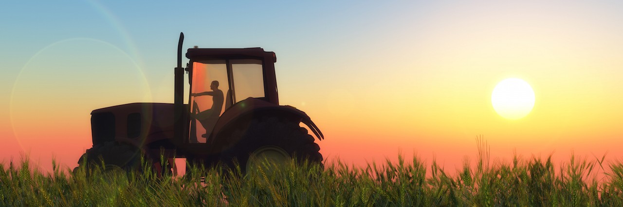 How Farming Taught Me to Live After the Suicide of a Childhood Friend a tractor riding through a wheat field at sunset