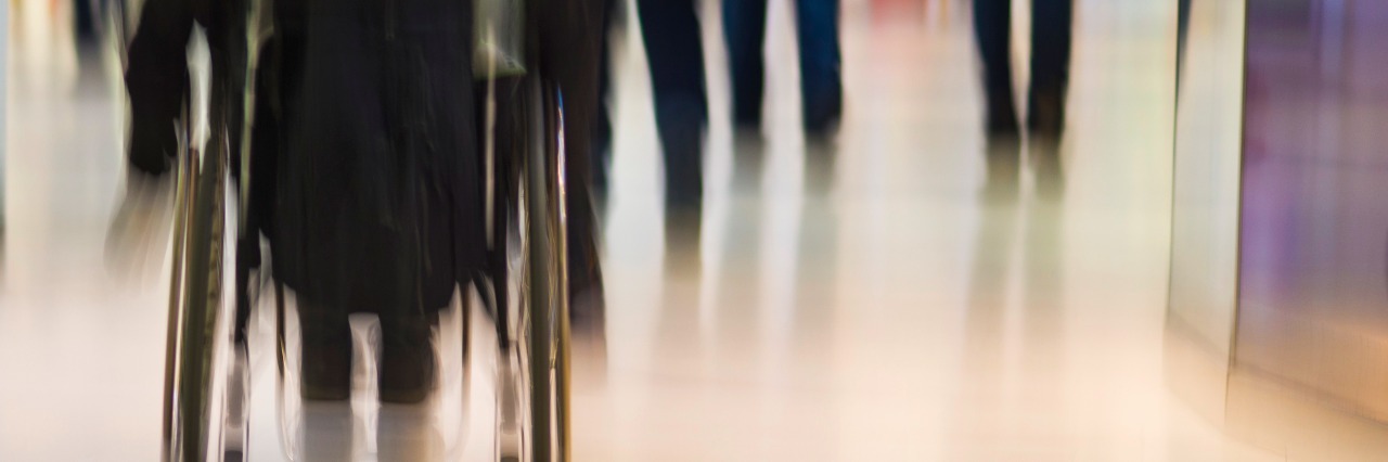 Rear view of person in wheelchair in public place in blured motion