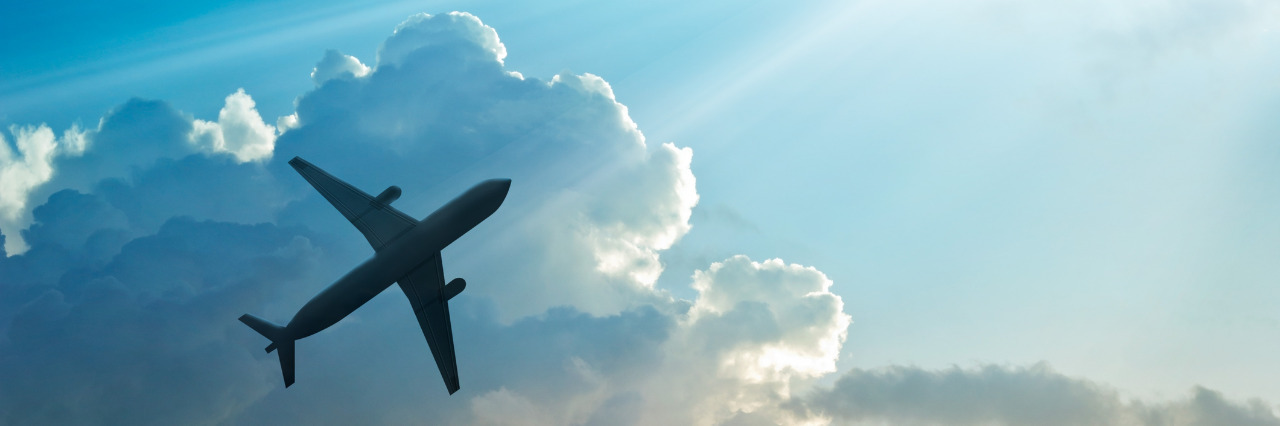 Traveling the World on the Autism Spectrum Airplane in the sky and clouds at sunrise.