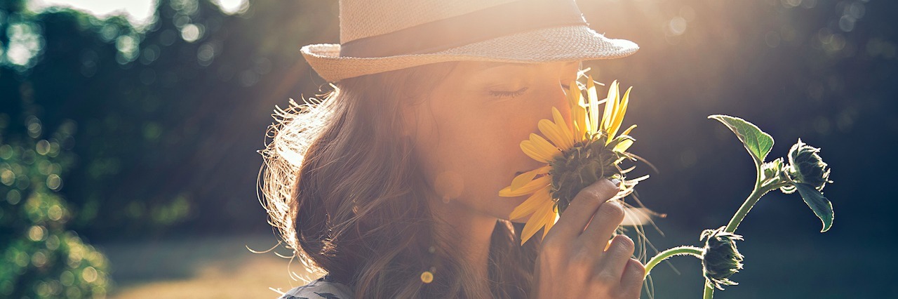 A girl smelling a sunflower.