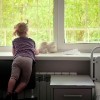 Little girl in a hospital ward looking at spring greens through the window and waiting for her parents to come
