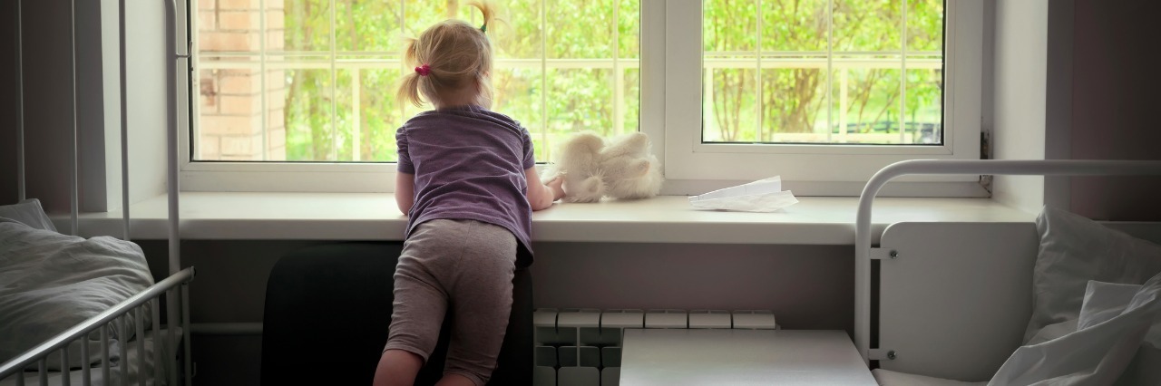 What It Feels Like to See an Otolaryngologist for a Cleft Palate Little girl in a hospital ward looking at spring greens through the window and waiting for her parents to come