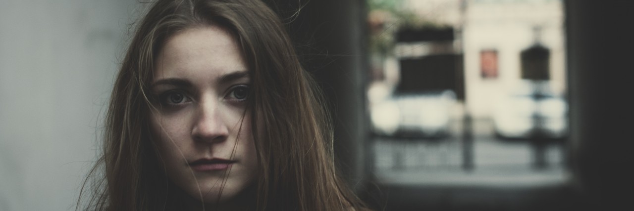 Feeling Alone and Isolated by PTSD Young pensive long haired scared girl standing outside alone