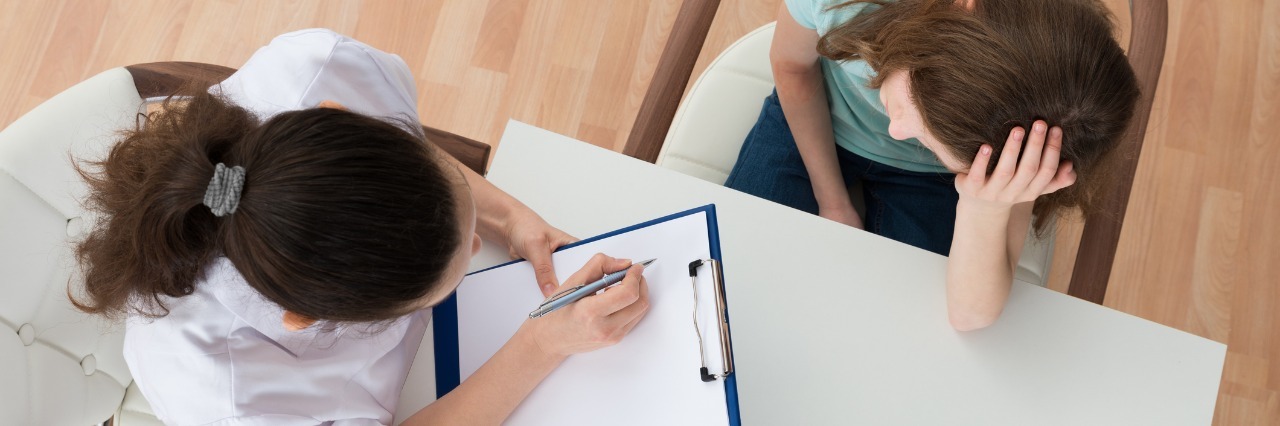 Trusting Doctors to Help as an Undiagnosed Patient patient talks to a doctor who is writing on her clipboard