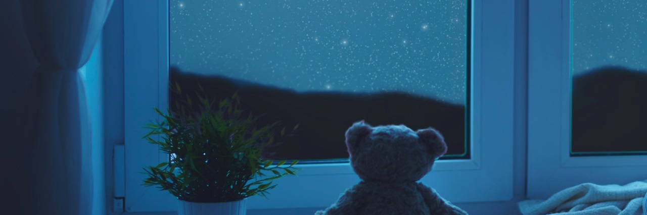 Stuffed bear at window facing moon and starry sky