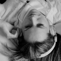 Young adult woman listening music with headphones in bed.