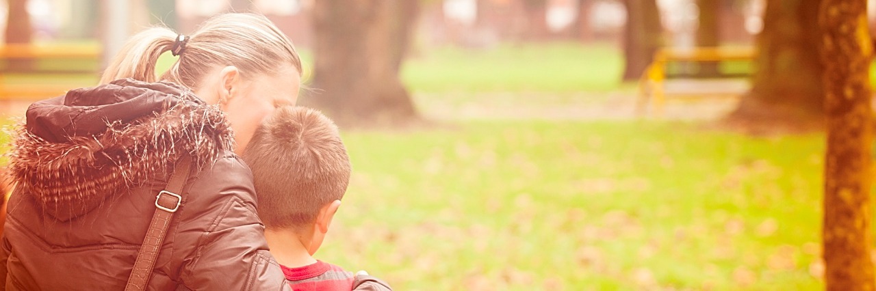 Why Parenting a Child With a Rare Illness Isn't Easy Mother and son walking at the park. Mother is embracing her son with head leaning against his.