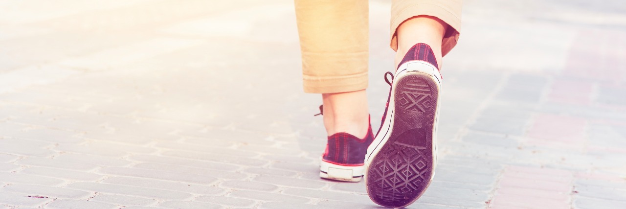 legs walking down street wearing pants and sneakers