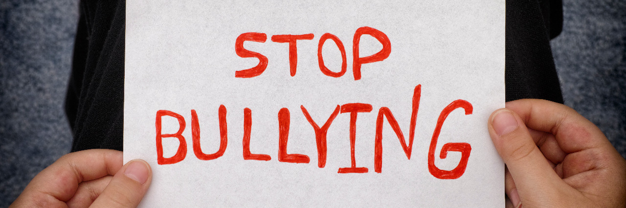 Letter to a Young Man With Down Syndrome Being Bullied at Work Boy holds Stop Bullying sign.